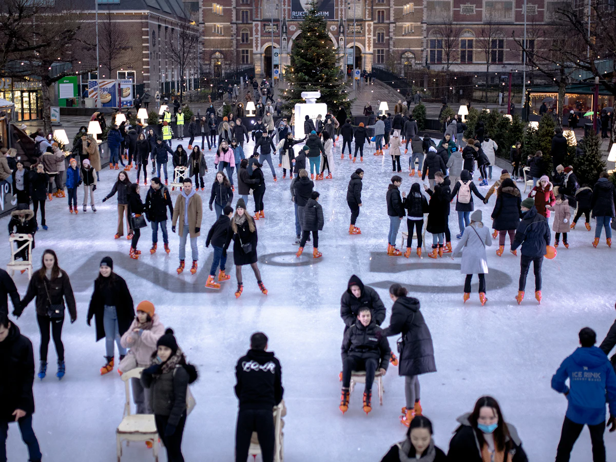 A busy outdoor ice rink full of skaters by day