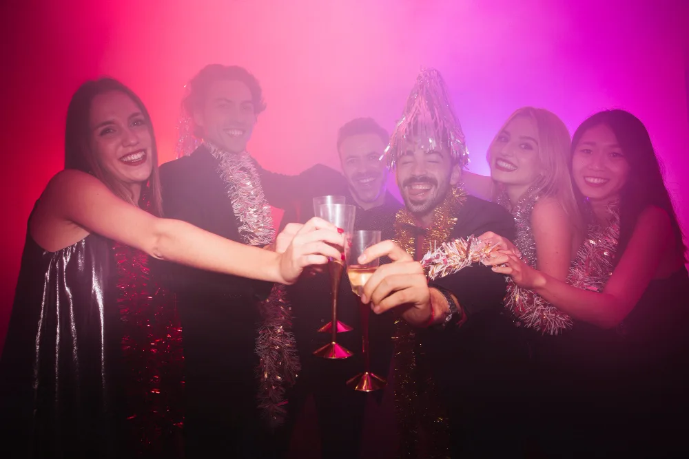 A group of friends in party attire toasting with champagne at a New Year's Eve club party